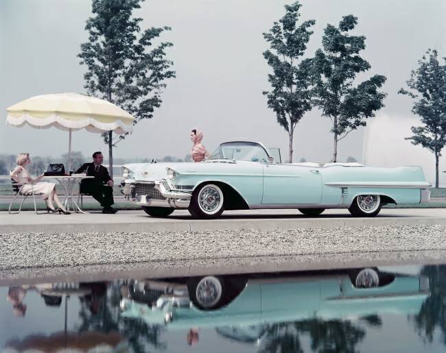 Side profile of a mid adult woman standing beside a Cadillac convertible anonymous