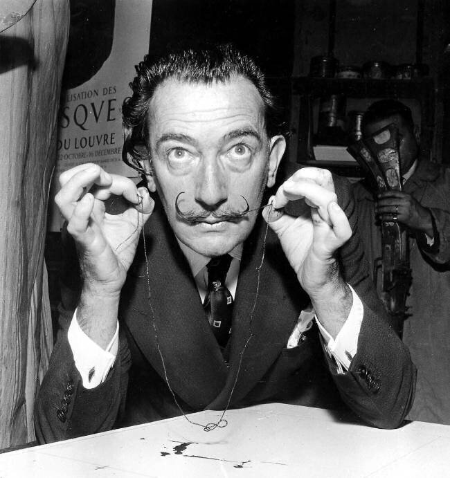 Le peintre Salvador Dali présentant une œuvre d'art qui sera détruite par le feu des mousquets le 16 novembre 1956. Rue des Archives