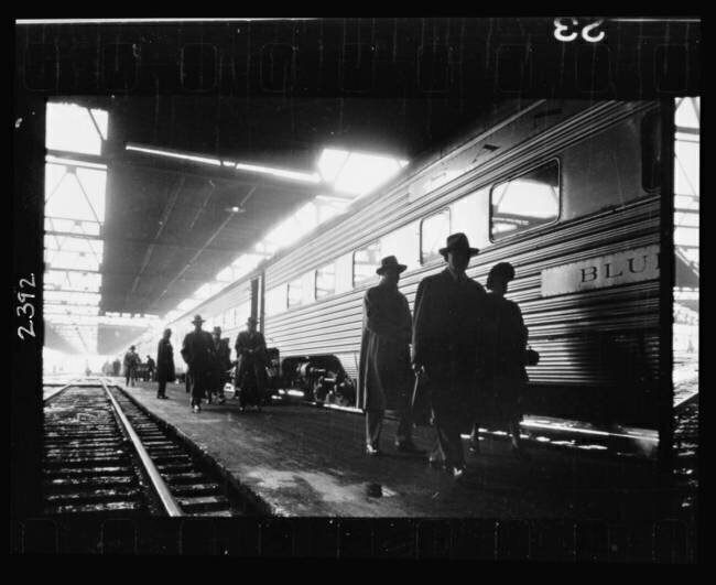 Hommes, probablement navetteurs, marchant le long du quai à côté d'un train Stanley Kubrick