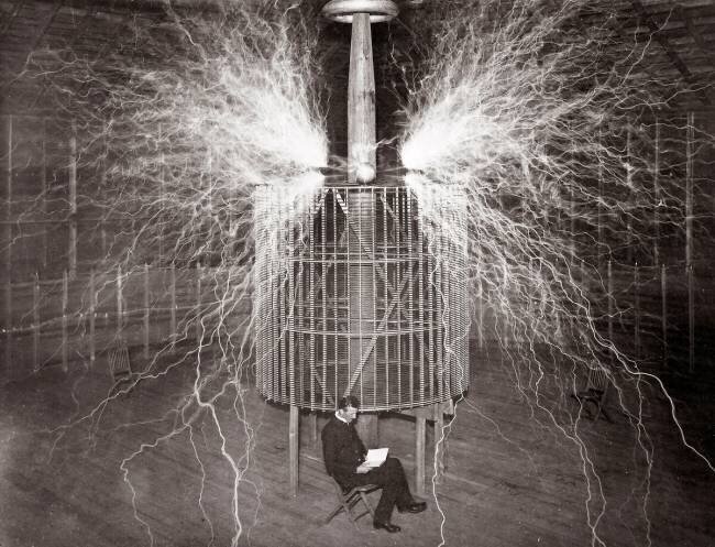 Nikola Tesla sitting in his Colorado Springs laboratory with his “Magnifying Transmitter” anonymous