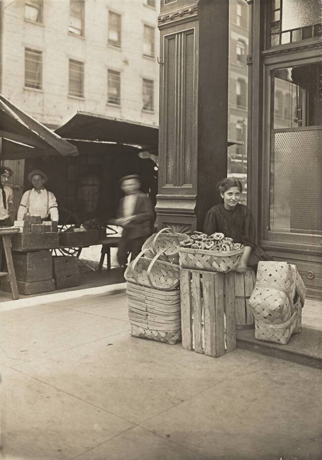 Lena Lochiavo, 11 years old, basket and pretzel seller, at Sixth Street market in front of saloon entrance, Cincinnati, Ohio, August 1908 Lewis Wickes Hine