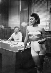 Modèle féminin, debout dans un bureau, fumant durant la confection de sous-vêtements (Stanley Kubrick) - Muzeo.com