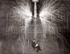 Nikola Tesla assis dans son laboratoire dans le Colorado Springs avec son 