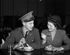 1940s smiling couple man soldier in army uniform and woman girlfriend sitting at soda fountain counter eating dish of ice cream (anonymous) - Muzeo.com